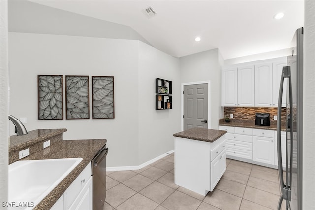 kitchen with white cabinets, a kitchen island, sink, and dark stone counters