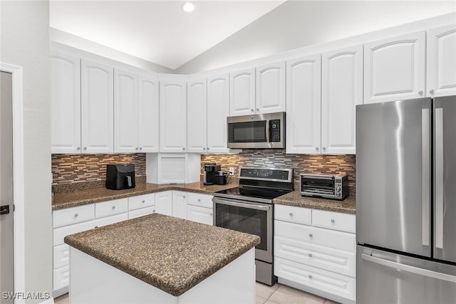 kitchen with tasteful backsplash, stainless steel appliances, white cabinetry, a kitchen island, and lofted ceiling