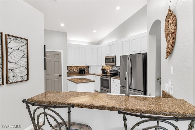 kitchen with a kitchen breakfast bar, kitchen peninsula, white cabinetry, and appliances with stainless steel finishes