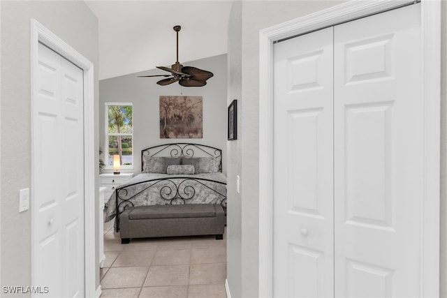 tiled bedroom featuring ceiling fan, lofted ceiling, and multiple closets