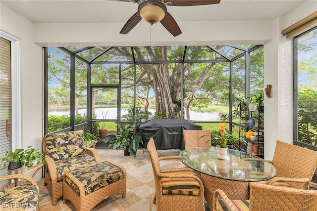 sunroom / solarium with ceiling fan and a water view