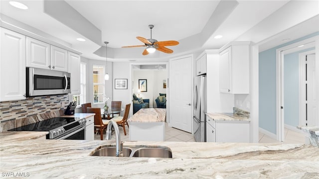 kitchen with appliances with stainless steel finishes, sink, white cabinets, decorative backsplash, and a raised ceiling