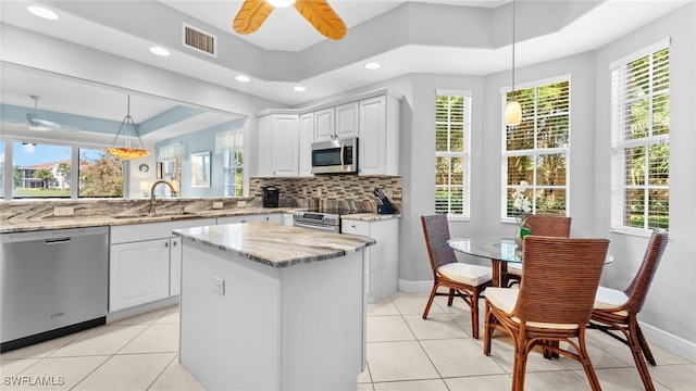 kitchen with white cabinetry, stainless steel appliances, sink, and hanging light fixtures