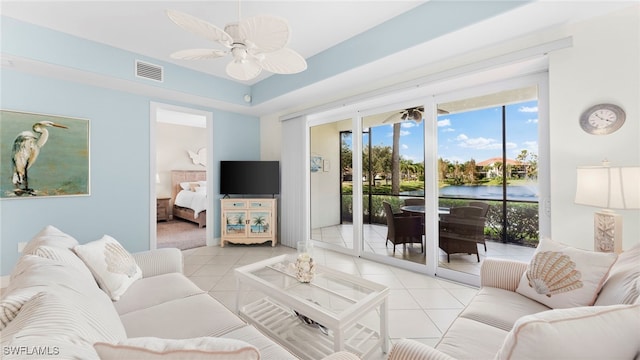 tiled living room featuring ceiling fan and a tray ceiling