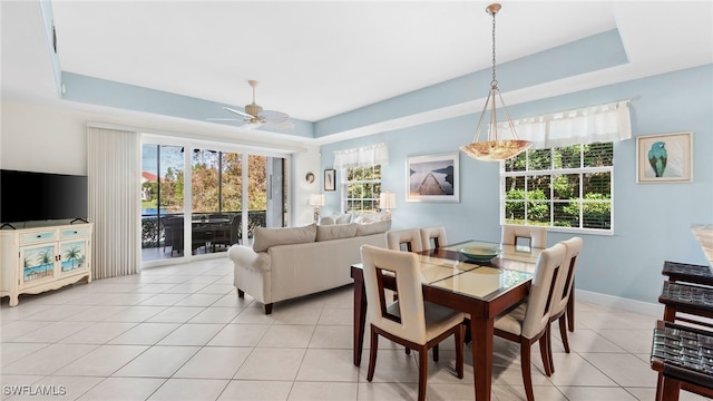 tiled dining room with ceiling fan, a raised ceiling, and a wealth of natural light