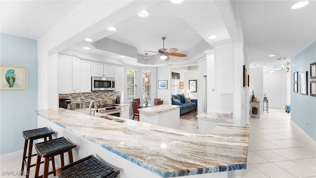 kitchen with stainless steel appliances, a raised ceiling, white cabinets, and kitchen peninsula