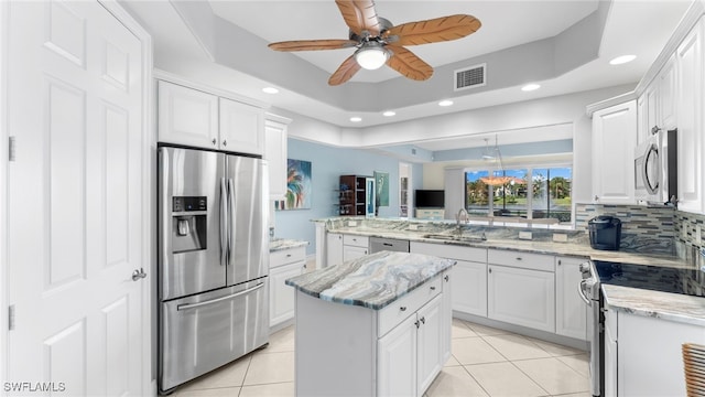 kitchen featuring a raised ceiling, white cabinetry, and appliances with stainless steel finishes