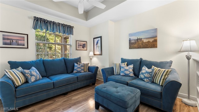 living room featuring a tray ceiling, dark wood-type flooring, and ceiling fan