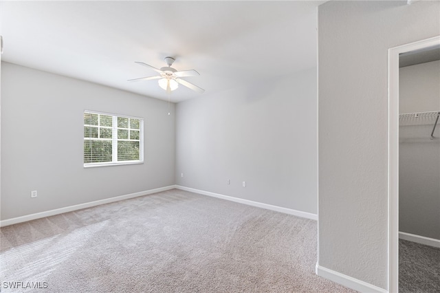 unfurnished bedroom with carpet, ceiling fan, a spacious closet, and a closet