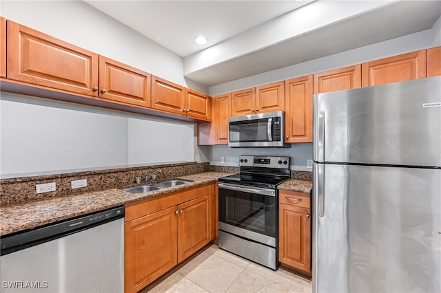 kitchen with appliances with stainless steel finishes, dark stone counters, and sink