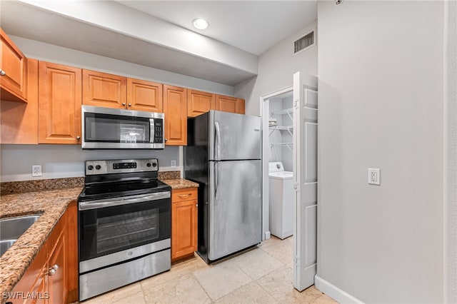 kitchen with light stone countertops, washer and dryer, and stainless steel appliances