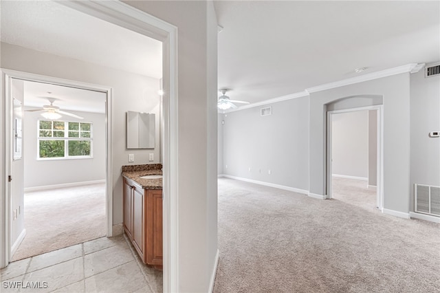 kitchen with stone counters, light carpet, ceiling fan, and ornamental molding