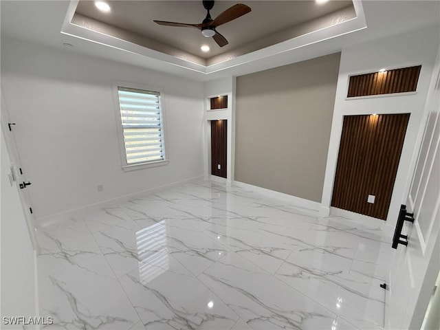 empty room featuring ceiling fan and a tray ceiling