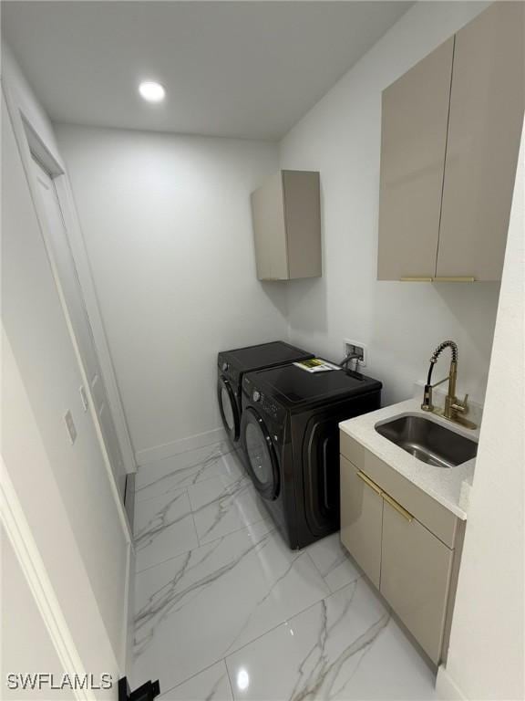 clothes washing area with sink, washing machine and dryer, and cabinets