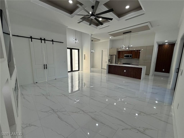 unfurnished living room featuring a towering ceiling, beamed ceiling, coffered ceiling, ceiling fan, and a barn door