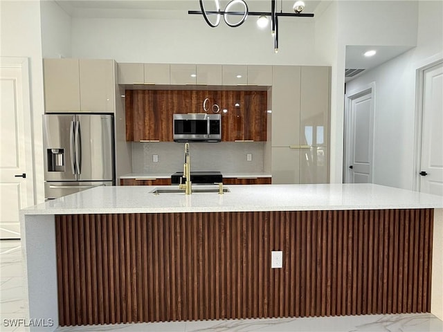 kitchen featuring tasteful backsplash, sink, a kitchen island with sink, and appliances with stainless steel finishes