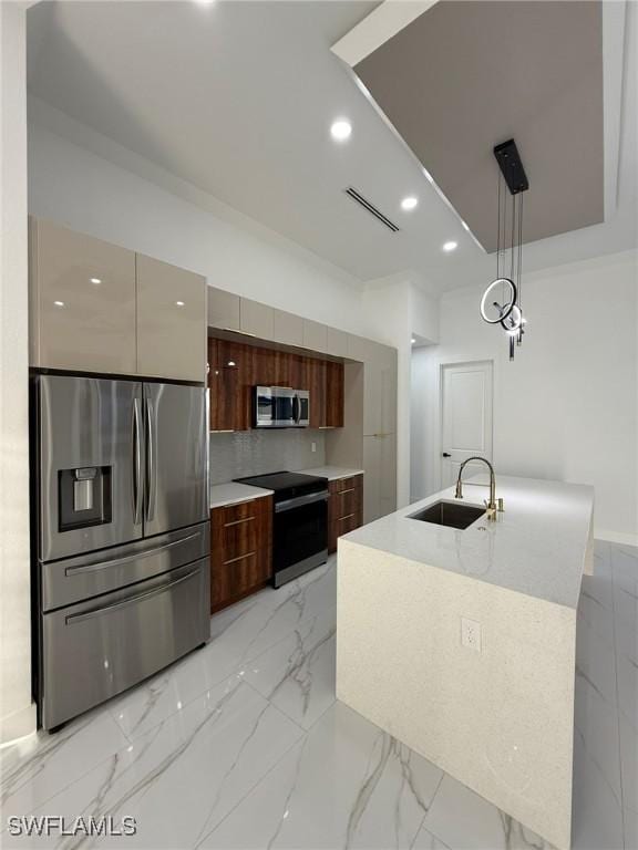 kitchen featuring appliances with stainless steel finishes, decorative light fixtures, tasteful backsplash, sink, and a kitchen island with sink