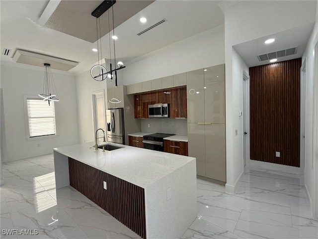 kitchen featuring pendant lighting, sink, appliances with stainless steel finishes, decorative backsplash, and a large island with sink