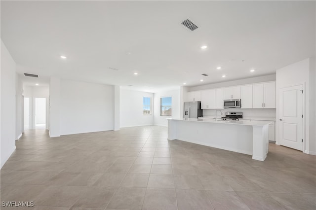 kitchen featuring white cabinetry, stainless steel appliances, light tile patterned floors, and an island with sink