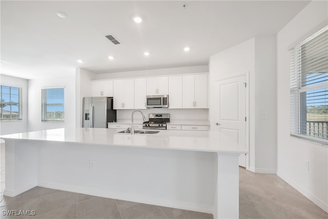 kitchen with white cabinets, stainless steel appliances, a spacious island, and sink