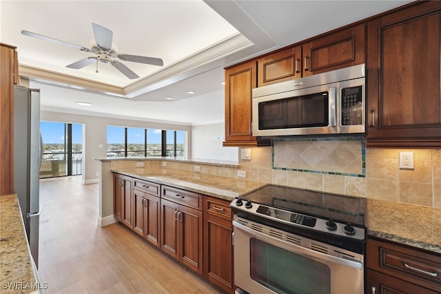 kitchen with kitchen peninsula, light stone counters, stainless steel appliances, and light hardwood / wood-style floors