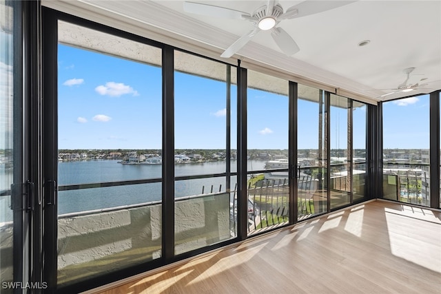 unfurnished sunroom featuring a water view, a wealth of natural light, and ceiling fan