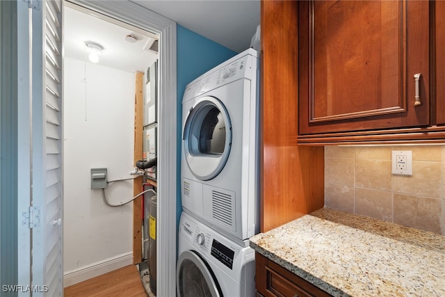 laundry area with stacked washer / dryer and light hardwood / wood-style floors