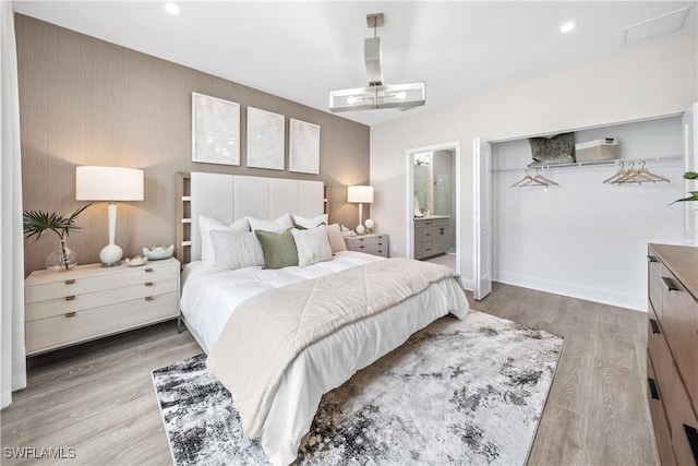 bedroom with ensuite bathroom and light hardwood / wood-style floors