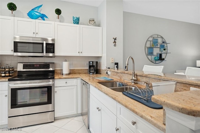 kitchen with decorative backsplash, appliances with stainless steel finishes, light stone countertops, sink, and white cabinets