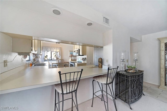 kitchen with a kitchen breakfast bar, kitchen peninsula, sink, and appliances with stainless steel finishes