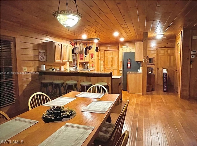 dining room featuring light hardwood / wood-style floors, wood ceiling, and wooden walls