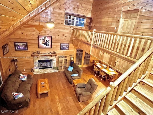 living room featuring wood walls, wood-type flooring, lofted ceiling, a fireplace, and wood ceiling