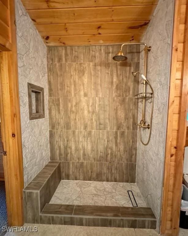 bathroom with a tile shower and wooden ceiling