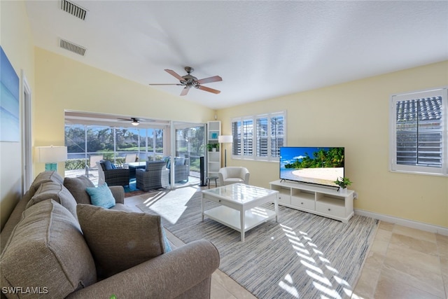 living room with a wealth of natural light, light tile patterned floors, ceiling fan, and lofted ceiling