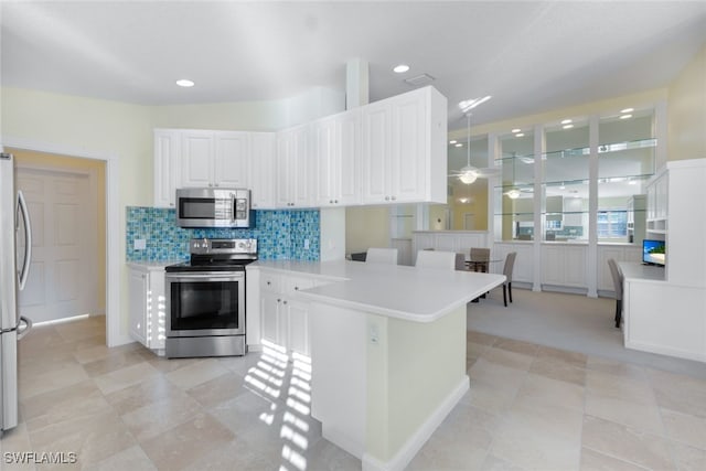 kitchen featuring appliances with stainless steel finishes, decorative light fixtures, white cabinetry, and tasteful backsplash