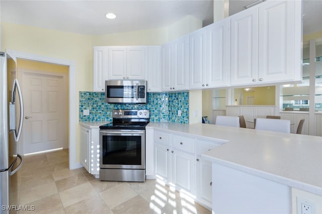 kitchen featuring decorative backsplash, white cabinetry, stainless steel appliances, and kitchen peninsula