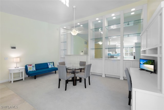 dining space with ceiling fan and light colored carpet