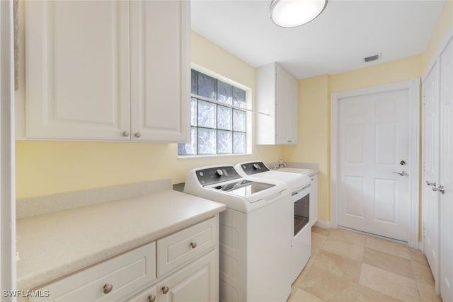 clothes washing area with cabinets and washing machine and dryer