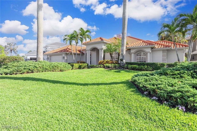 mediterranean / spanish home with a garage and a front lawn