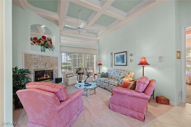 living room featuring beamed ceiling, a towering ceiling, light tile patterned floors, and a high end fireplace