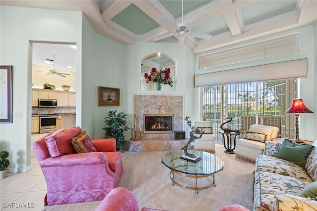 tiled living room with a high ceiling, coffered ceiling, crown molding, a premium fireplace, and beam ceiling