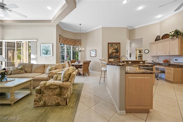 kitchen with a breakfast bar, light brown cabinets, light tile patterned floors, pendant lighting, and dark stone countertops