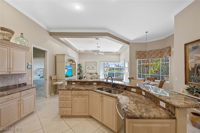 kitchen featuring pendant lighting, dark stone counters, sink, an island with sink, and light brown cabinetry