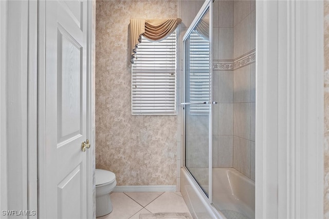 bathroom featuring tile patterned floors, toilet, and combined bath / shower with glass door