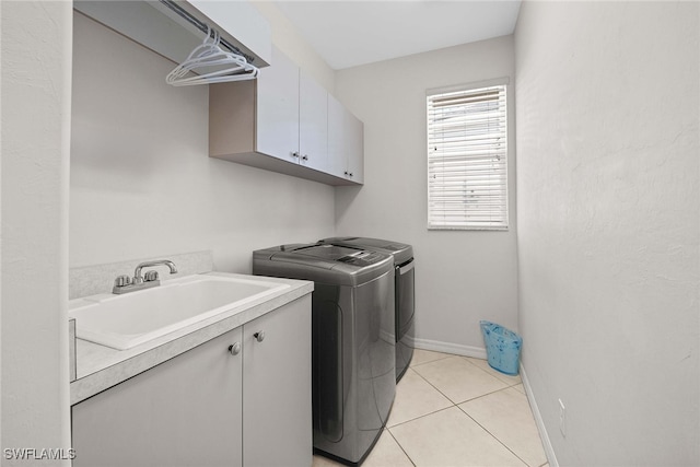 clothes washing area featuring cabinets, independent washer and dryer, sink, and light tile patterned floors