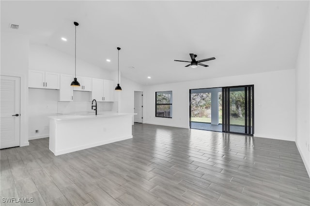 unfurnished living room with ceiling fan, light hardwood / wood-style floors, sink, and vaulted ceiling