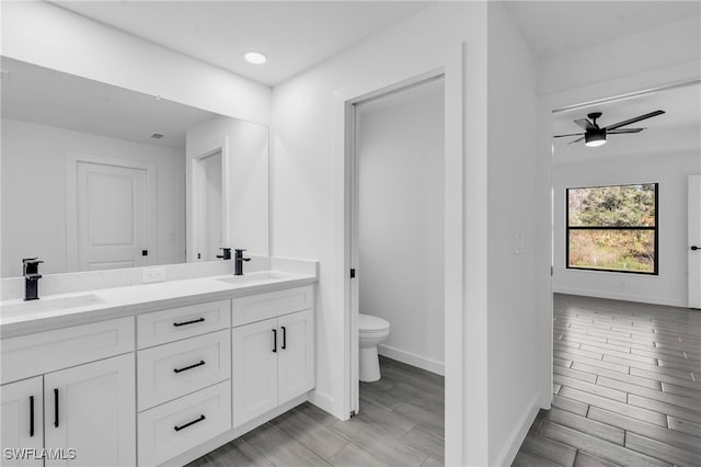 bathroom featuring hardwood / wood-style flooring, ceiling fan, toilet, and vanity