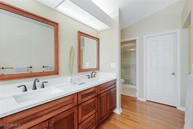 bathroom featuring walk in shower, wood-type flooring, lofted ceiling, toilet, and vanity