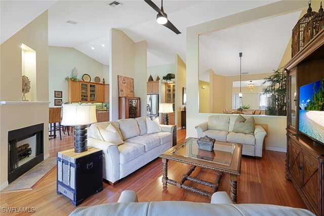 living room with hardwood / wood-style flooring, vaulted ceiling, and ceiling fan