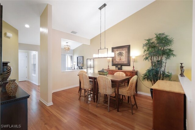 dining space with a chandelier, wood-type flooring, and high vaulted ceiling